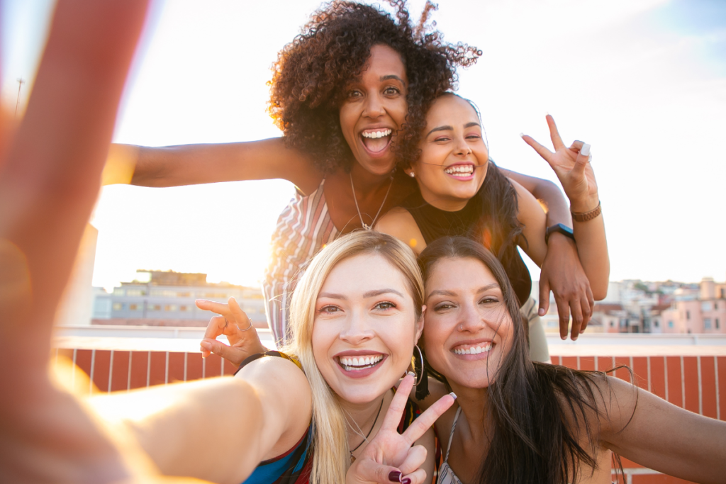 4 ragazze stanno insieme e sorridono per scattarsi un selfie